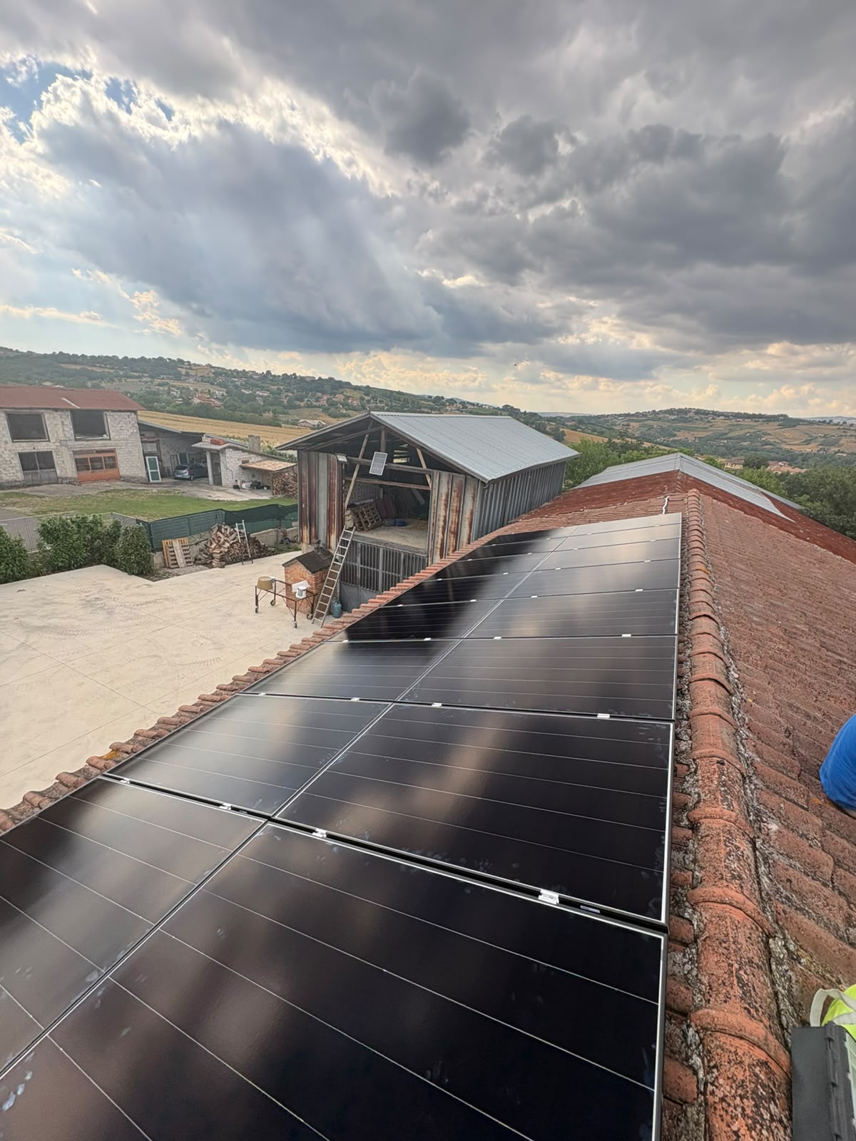 Moduli fotovoltaici all-black su tetto in tegola con vista sulla campagna
